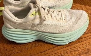 Hoka Bondi 8 storlek 38.5 - Snygga vita sneakers från Hoka i storlek 38,5 med extra tjock, ljusgrön sula och ventilerande mesh-ovandel. Skorna har diskreta detaljer i gult och en modern, sportig look. Perfekta för dig som gillar streetstyle och komfort.(i färgställningen Eggnog / Oat Milk med ljusgröna/mintgröna detaljer på mellansulan). Använda men i bra skick säljer dom nytvättade  