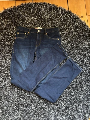 Levi's 512 Slim Taper mörkblå jeans - Säljer ett par Levi's 512 Slim Taper jeans i mörkblå denim. Modellen har smal passform med avsmalnande ben, klassiska fem fickor och kontrastsömmar. Perfekta för dig som gillar en clean och stilren look. Är i nyskick och knappt använda. Hör av er vid frågor!