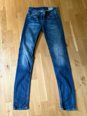Blå slim fit jeans från G-Star RAW - Snygga blå slim fit jeans från G-Star RAW med klassisk femficksmodell och slitningar på låren. Jeansen har inte stretch. Perfekta för en avslappnad och trendig look ✨
