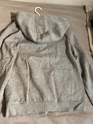Grå hoodie från Nike XL youth 158/170 - Säljer en enkel och stilren grå hoodie från Nike i storlek XL i barnstolek  passar storlekarna från 158-170. Hoodien har en klassisk huva och är gjord i mjukt material som känns skönt mot huden. Perfekt för dig som gillar sportig och avslappnad stil. Tröjan är helt ny och aldrig använd pga fel stolek köpt för 900kr