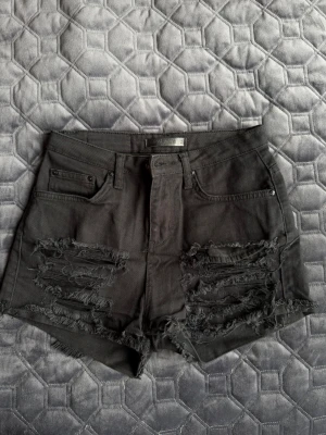 Svarta jeansshorts - Säljer ett par svarta högmidjade jeansshorts från Perfect Jeans. Shortsen har slitna detaljer och klassisk femficksdesign. 