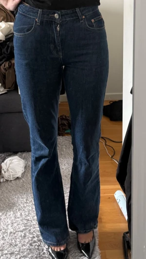 Mörkblå bootcut jeans - Snygga mörkblå bootcut jeans med klassisk femficksdesign och hög midja. Jeansen har raka ben som slutar i en lätt utsvängd form och stängs med knapp och dragkedja. Perfekta till sneakers eller klackar för en trendig look.