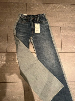 Blå raka jeans med hög midja med hela 60% - Säljer ett par klassiska blå jeans med raka ben och hög midja. Jeansen har fem fickor, knappgylf och en snygg tvättad look. Materialet är kraftig denim i bomull. Perfekta för dig som gillar en avslappnad och trendig stil.
