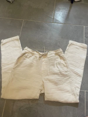 Beige mjukisbyxor - Säljer ett par beige mjukisbyxor med resår i midjan. Byxorna har två sidofickor och är gjorda i ett mjukt, strukturerat tyg som känns riktigt bekvämt. Perfekta för chill dagar eller när du vill ha det extra soft.