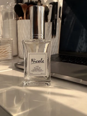 Nicole 01 Eau de Parfum 50 ml - Nicole 01 Eau de Parfum i en elegant, genomskinlig glasflaska med silverfärgad spraykork. Doften är inspirerad av Gabriela Sabatini och flaskan rymmer 50 ml. Perfekt för dig som gillar klassiska och fräscha parfymer.
