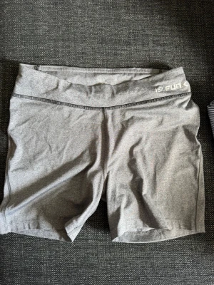 Grå träningsshorts med dragkedja - Snygga grå träningsshorts i stretchigt material med bred midja och diskret logga framtill. Shortsen har en praktisk dragkedjeficka baktill och är perfekta för aktiva dagar. Passformen är normal och materialet känns mjukt mot huden. Skriv privat för fler bilder eller om du har några frågor💗