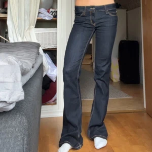 Cheap Monday jeans - Säljer ett par mörkblå bootcut jeans från Cheap Monday med låg midja och klassiska kontrastsömmar. Jeansen har fem fickor och är tillverkade i stretchig bomullsdenim för en snygg passform. Perfekta för dig som gillar en retro vibe och markerad siluett. Slutsålda!🤗uppsprättade där nere så de är långa på mig som är 165🥰