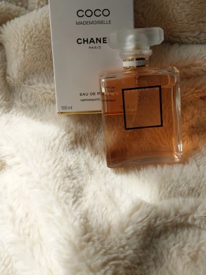 Coco Mademoiselle Eau de Parfum 100ml - Coco Mademoiselle Eau de Parfum från Chanel i en elegant, genomskinlig glasflaska med guldiga detaljer och vit kork. Om du köper denna chanel parfym får du en la rive happy vibes mist också med i köpet 