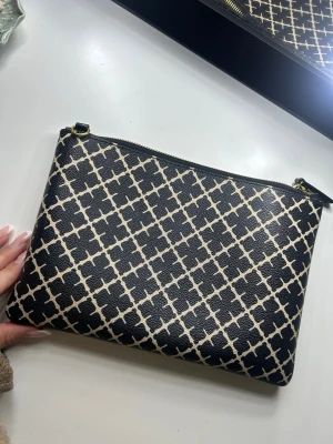 Svartvit kuvertväska By Malene Birger - Snygg kuvertväska från By Malene Birger i svart och vitt med grafiskt mönster. Väskan har guldfärgad dragkedja och är tillverkad i ett tåligt konstlädermaterial. Den är i bra skick men lite smutsig på insidan. Pris går att diskutera💕 Nypris 900kr