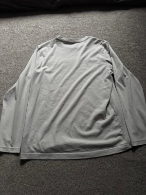 Ljusgrå långärmad topp - En enkel och stilren ljusgrå långärmad topp i mjukt material. Perfekt basplagg att matcha med olika outfits. Rak passform och rund halsringning.