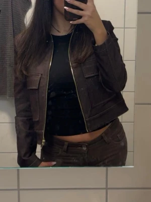 Mörkbrun jeansjacka med dragkedja - Snygg mörkbrun jeansjacka med raka linjer och två stora bröstfickor. Jackan har en stilren dragkedja framtill och klassisk krage. Perfekt för dig som vill ha en cool och tidlös look. Köpt från zara för 799 och använd 1 gång 