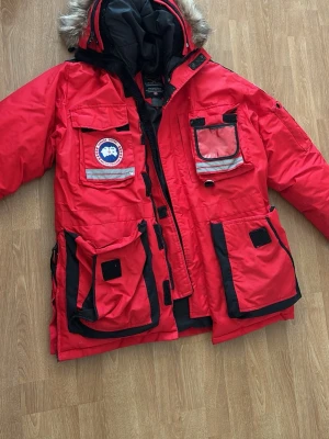 Canada Goose Arctic Program vinterjacka – Röd – Storlek M/L/XL - Men/Women - Säljer en varm och exklusiv röd Canada Goose Arctic Program vinterjacka. En riktigt klassisk vinterjacka som är perfekt för kalla dagar tack vare sin rejäla isolering och höga krage.  🔴 Färg: Röd 📏 Storlek: Märkt Medium/Large (passar även Large/XL beroende på passform) ❄️ Modell: Arctic Program 🔥 Varm och bekväm vinterjacka för höst/vinter 🧥 Klassisk design med hög kvalitet och funktion Jackan är i fint skick och har använts varsamt. Perfekt för dig som vill ha en varm och samtligt skön jacka.