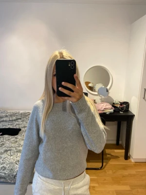 Ljusgrå stickad tröja Vero Moda - Mysig ljusgrå stickad tröja från Vero Moda i storlek XS. Tröjan har en enkel och klassisk design med rund halsringning och ribbade muddar vid ärmslut och nederkant. Perfekt för lager på lager och passar till det mesta i garderoben.