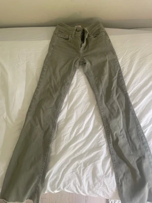 Gröna bootcut jeans med broderade fickor - Säljer ett par gröna bootcut jeans med snygga broderade detaljer på bakfickorna. Jeansen har klassisk femficksdesign. I storlek 32/xxs. De är dock avklippta längst ner några cm. Pris kan diskuteras😁