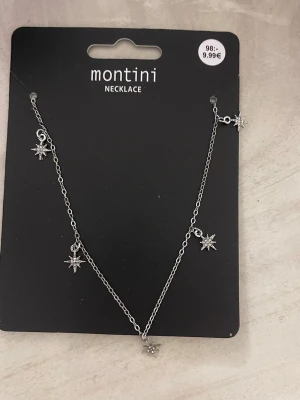 Silverfärgat halsband med stjärnhängen - Snyggt halsband från Montini i silverfärg med flera små stjärnformade hängen. Kedjan är tunn och smidig, och stjärnorna har glittrande detaljer som ger en cool touch till din outfit.