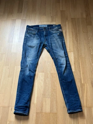  slim fit Replay jeans med slitningar - Snygga blå slim fit jeans med slitningar och tvättade detaljer. Klassisk femficksmodell med dragkedja och knapp i midjan. Jeansen har en modern passform och är tillverkade i denim med lätt stretch för extra komfort. Storlek 32/32 men sitter som 30/32.