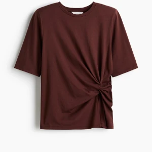 Vinröd topp med knytning - Säljer en vinrld kortärmad topp från H&M med en fin knytning på sidan. Den har även vaddering i axlarna. Helt ny och oanvänd med prislapp, tyckte den var för liten så har ej kommit till användning💗