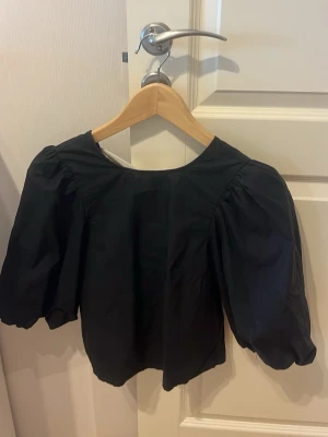 En snygg festblus med öppen rygg från H&M - En snygg festblus med öppen rygg som har två rosetter. Den har endast användts 1 gång! Den är i väldigt bra skick!