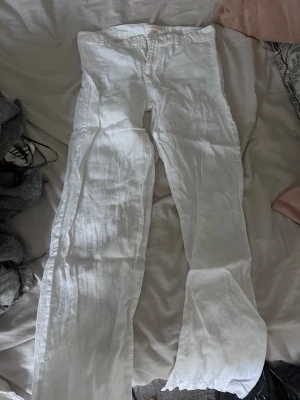Vita linnebyxor med raka ben - Säljer ett par vita linnebyxor med raka ben. Byxorna har klassisk knappgylf och är tillverkade i ett luftigt linnetyg som passar perfekt till sommaren. Stilrena och enkla att matcha med olika toppar.