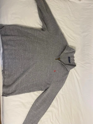 Grå stickad tröja Polo Ralph Lauren - Snygg grå stickad tröja från Polo Ralph Lauren med halv dragkedja och klassisk röd logga på bröstet. Tröjan har hög krage och långa ärmar, perfekt för lager på lager. Materialet är mjukt och bekvämt, passar till många olika stilar. Bara att höra av sig vid funderingar!😁