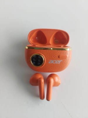 Orange trådlösa in-ear hörlurar - Snygga orange trådlösa in-ear hörlurar med matchande laddningsetui. Etuiet har en digital display och guldfärgade detaljer. Hörlurarna har en stilren, modern design och passar perfekt för musik och samtal på språng.