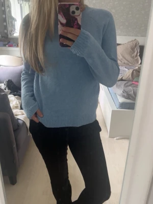 Ljusblå stickad tröja - Mysig ljusblå stickad tröja med rund halsringning och ribbade muddar vid ärmslut och nederkant. Tröjan har en enkel och clean design, perfekt att matcha med jeans eller kjol. Materialet ser mjukt och bekvämt ut, och modellen är något lösare för en avslappnad vibe.