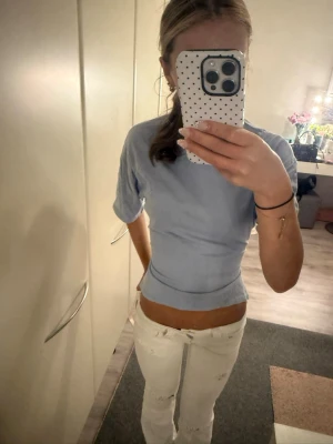 Ljusblå croppad topp med knyt - Trendig ljusblå croppad topp med korta ärmar och snygg knytning i ryggen. Toppen har en figurnära passform och är perfekt för dig som vill ha en cool och modern look. Tillverkad i mjukt material som känns skönt mot huden.