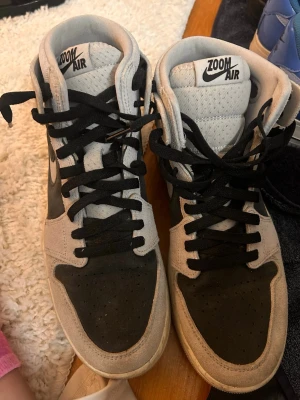 Nike Zoom Air höga sneakers svart/grå - Nike Zoom Air sneakers i högt utförande med svart och grå mocka samt textil. Klassisk Swoosh på sidan och svart snörning. Tungan har Zoom Air-logga och sulan är vit. Perfekta för dig som gillar streetwear och vill ha en clean look.