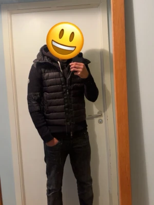 Svart dunjacka med huva - Snygg svart dunjacka med quiltad kropp och stickade ärmar. Jackan har dragkedja framtill, två fickor med knappar och en stor huva med dragsko. På vänster ärm sitter en rund patch. Perfekt för kalla vinterdagar. ‼️‼️ sist bilderna när mobilen e på Moncler märker e pgv att jag la in en annan länk ist för vanliga hemsidan för jag tyckte det var skoj. Enkelt att ändra tillbaka med en tutorial på YouTube ‼️‼️
