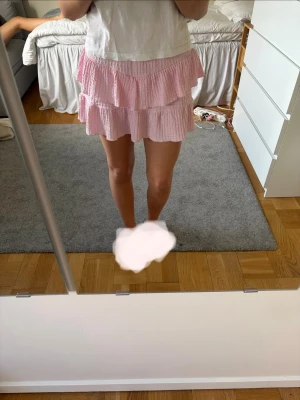 Ljusrosa volangkjol med struktur - Supersöt ljusrosa kortkjol med två volanglager och strukturerat tyg. Kjolen har en avslappnad passform och är perfekt för dig som gillar en feminin och lekfull stil. Passar till både enkla toppar och stickade tröjor. Storlek 13-14 år / 164 cm men sitter som xs 