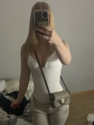 Vit body  - Säljer en vit body med djup urringning och smala axelband. Bodyn har en tight passform och är tillverkad i ett stretchigt material som sitter snyggt på kroppen. Perfekt att styla med jeans eller kjol för en trendig look.