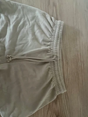 Beige shorts med snörning - Snygga beige shorts med bred resår i midjan och justerbar snörning framtill. Tillverkade i mjukt material som känns skönt mot huden. Perfekta för varma dagar och enkel att matcha med olika toppar.