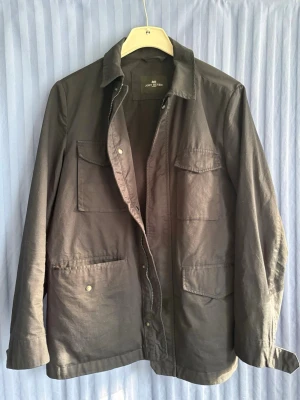 JOHN HENRIC Mörkblå overshirt med fickor - Stilren mörkblå overshirt med fyra stora fickor framtill och klassisk krage. Jackan har dragkedja och knappar, samt lång ärm. Perfekt för lager-på-lager och enkel att matcha till olika outfits.