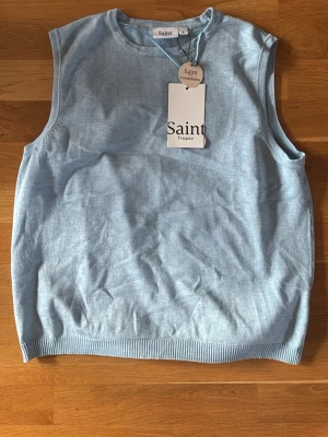 Ljusblå stickad väst från Saint Tropez - Snygg ljusblå stickad väst från Saint Tropez. Västen har rund halsringning och ribbade kanter nedtill och vid ärmöppningarna. Perfekt att styla över en skjorta eller t-shirt för en clean look.