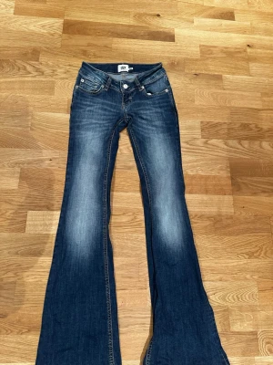 Blå utsvängda bootcut  jeans  - Säljer ett par blå bootcut jeans med utsvängda ben. Jeansen har klassisk femficksmodell, låg midja och ljusare tvättade partier på låren. Jeansen är från lager 157. Säljer dem för tyvärr har den inte kommit till andvändväning.