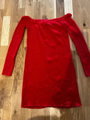 Röd offshoulder klänning Dennis Maglic - Snygg röd offshoulder klänning från Dennis Maglic i ribbad stretchig kvalitet. Klänningen har lång ärm och kroppsnära passform, perfekt för dig som vill sticka ut. 