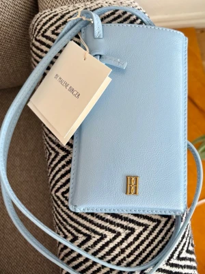 By Malene Birger Aya Ljusblå Mobilväska i Läder - Helt ny med tags enligt bilder!  Tillverkad i 100% läder.  Färg: Dream Blue  Mått:  17x10,5x1,5cm  Nypris: 1800kr  Se gärna mina övriga annonser för bundlerabatter och samfrakt!