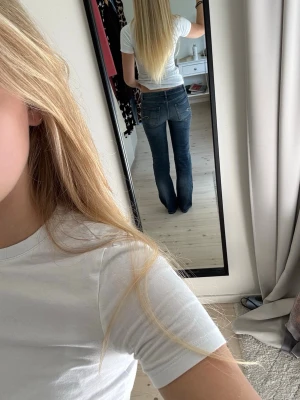 Mörkblå bootcut jeans - Säljer ett par lågmidjade mörkblå bootcut jeans med klassisk femficksdesign och snygga sömmar på bakfickorna. Jeansen har en utsvängd passform nedtill och sitter tajt över höfterna. Jeansen är använda men har inga defekter. Ser ingen storlek i byxorna men skulle uppskatta som S. Som referens är jag 163 cm lång.