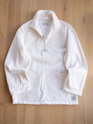 White Sailing Shirt, size S/M - Tjock seglar-skjorta i kraftig bomull med lång ärm och öppen krage. Skjortan har en knappdetalj framtill och praktiska fickor på sidorna. Perfekt för en avslappnad och stilren look. Står XS, men väldigt rymlig så snarare S/M ( se mått )