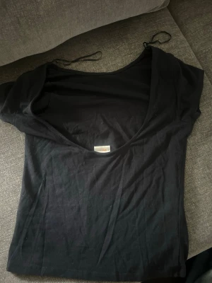 Marinblå T-shirt med öppen rygg - En marinblå T-shirt med öppen rygg. Tillverkad i mjukt bomullstyg som känns bekvämt mot huden. Perfekt att matcha med jeans eller kjol för en clean och stilren look.