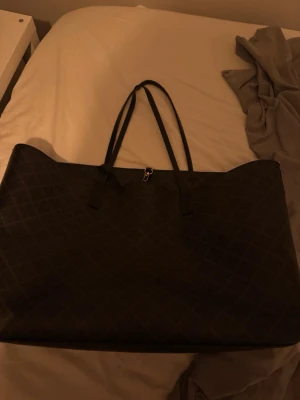 By malene Birger väska  - Snygg och rymlig shoppingväska i svart med diskret rutmönster. Väskan har dubbla långa handtag i svart konstläder och dragkedja upptill. Perfekt för att bära med sig allt man behöver under dagen. Materialet känns tåligt och lätt att hålla rent. Nypris 3400kr (abi modellen)