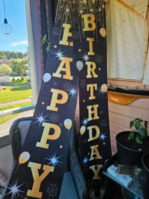 Happy Birthday banderoller svart/guld - Två långa banderoller med texten 'Happy Birthday' i stora guldfärgade bokstäver på svart bakgrund. Dekorerade med ballonger, stjärnor och fyrverkerier i vitt och guld. Perfekt för att dekorera till födelsedagsfesten.