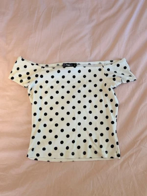 Prickig offshoulder topp från FB Sister - Säljer en vit offshoulder topp från FB Sister med svarta prickar. Toppen är kortärmad och har en figurnära passform. 