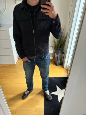 Marinblå overshirt från Jack and Jones - Stilren marinblå overshirt från Jack and Jones med dragkedja framtill och två bröstfickor med lock. Klassisk krage och raka ärmar. Perfekt att slänga över en t-shirt för en clean look. 