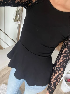Svårt tröja med spets armar och volang - Säljer min svart tröja från ginatricot. Den har en volang längst ner och svarta spetsarmar. Inge defekter. Är i storlek XS.