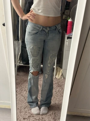 Ompysslade LTB jeans - Säljer ett par ljusblå jeans med raka ben och stora slitningar på båda benen. Jeansen har klassisk femficksmodell och är tillverkade i denim. Perfekta för en avslappnad och trendig look.
