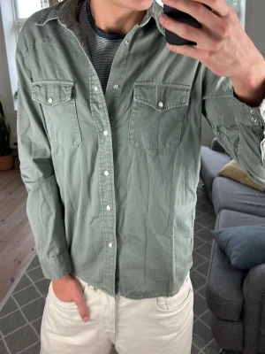 Jeansskjorta Olivgrön  - Trendig och supersnygg! Mått: A:51 B:50 C:50 D:62 (cm) Skriv vid fundering! 😇🙌