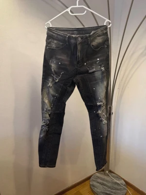 Svarta skinny jeans med slitningar - Säljer ett par svarta jeans med slitningar och vita färgstänk. Dom är använda en gång och i helt nytt skick! Säljer dom för dom inte riktigt är min stil! Pris går att diskutera 