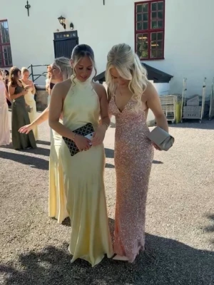 Ljusgul lång satinklänning balklänning  - Använd under få timmar perfekt nu inför balen för er som tar studenten💛Elegant ljusgul långklänning i satin med halterneck och öppen rygg. Klänningen har en mjuk, glansig finish och ett följsamt fall som ger en lyxig känsla. Perfekt för bal eller festliga tillfällen där du vill sticka ut❤️.