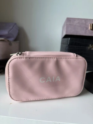 Ljusrosa necessär från CAIA - Söt ljusrosa necessär från CAIA i glansigt material med dragkedja. Perfekt för smink eller småprylar. Rektangulär form och enkel design med CAIA-logga på framsidan.